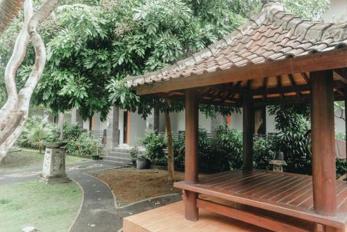 a wooden gazebo with a bench in a garden at Hotel Diana 2 in Kesiman