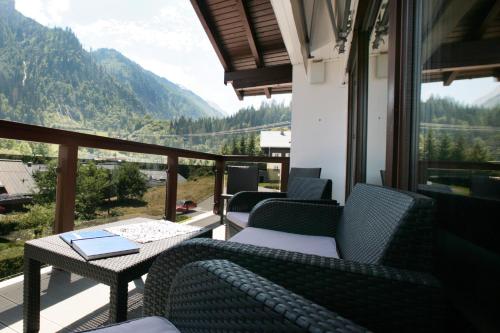 a balcony with chairs and a table with a book at Chalet Sabrina mit Außenpool im Sommer in Kaprun