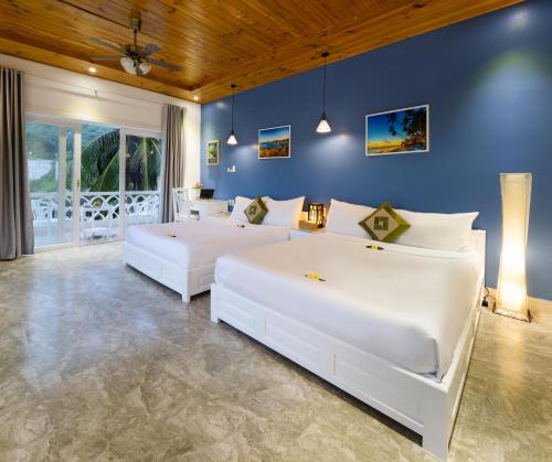 two beds in a bedroom with blue walls at Casa Maya Resort in ThÃ´n Báº£o An