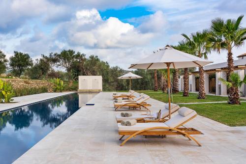 a group of lounge chairs and umbrellas next to a swimming pool at Il San Corrado di Noto in Noto