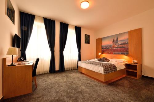 a bedroom with a bed and two large windows at Hotel Orient Zagreb in Zagreb