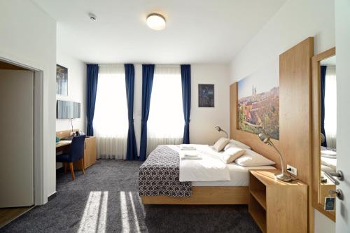 Schlafzimmer mit einem Bett, einem Schreibtisch und Fenstern in der Unterkunft Hotel Orient Zagreb in Zagreb
