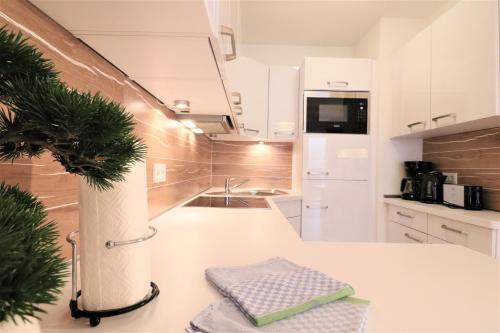 a kitchen with white cabinets and a plant on a counter at Alpin & See Resort - Pinzgau Holidays in Zell am See