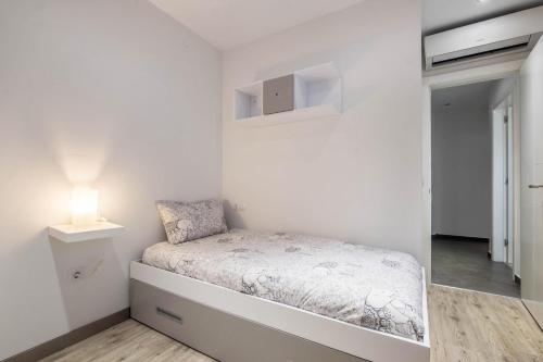 a white bedroom with a bed and a lamp at Casa Tiago in Santa Cruz de Tenerife