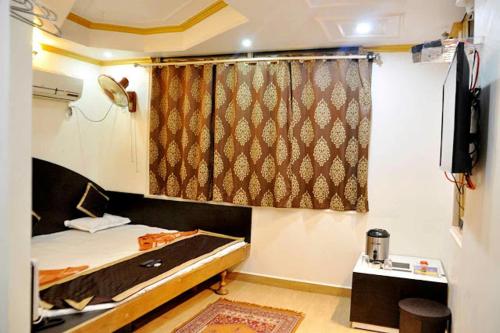 een kleine slaapkamer met een bed en een raam bij Hotel Vijayshree in Pachmarhī