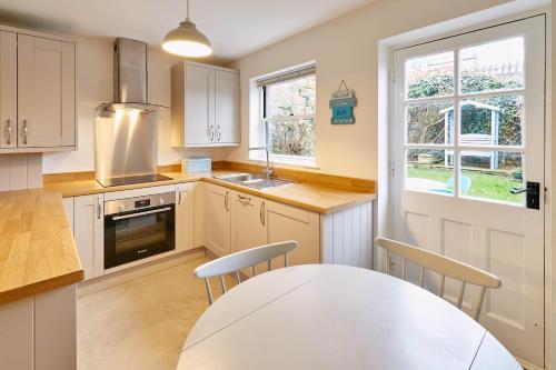 a kitchen with white cabinets and a table with chairs at Host & Stay - Richemont Cottage in Whitby