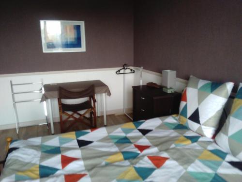 une chambre avec un lit avec une couette colorée dans l'établissement Les Couesnons, à Pontorson