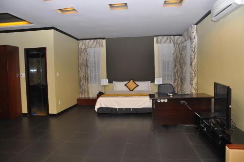 a bedroom with a bed and a dresser and a desk at Monte Carlo Hotel Hai Phong in Hai Phong