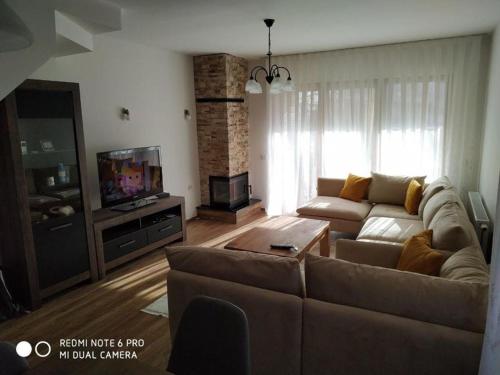 a living room with a couch and a tv at Brezovica Luxury Villa, Brezovicë in Brezovicë