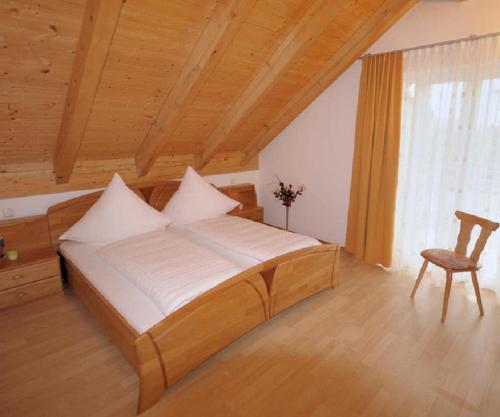 sypialnia z dużym łóżkiem i krzesłem w obiekcie Deinerhof w mieście Hauzenberg