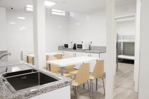 una cocina con una mesa y sillas blancas y una encimera. en Albergue Logroño Centro, en Logroño