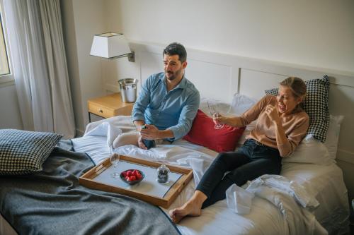a man and a woman sitting on a bed with a tray at Gallery Hotel in Barcelona