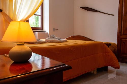 a bedroom with a bed with a lamp on a table at La Masseria Hotel Ristorante Centro Benessere in Cocumola