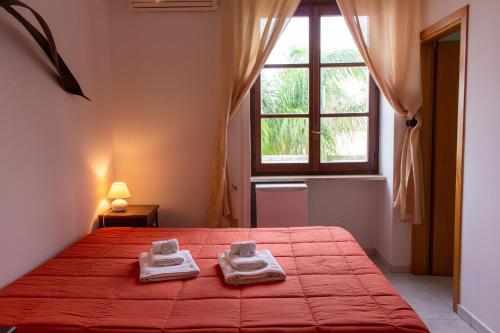 a bedroom with a red bed with two towels on it at La Masseria Hotel Ristorante Centro Benessere in Cocumola