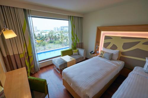 a hotel room with a bed and a large window at Novotel Chennai OMR in Chennai