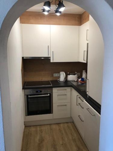 a kitchen with white cabinets and a black oven at Elto Appartements in Kaprun