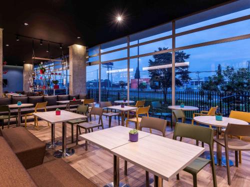 a restaurant with tables and chairs and large windows at ibis Chia in Chía