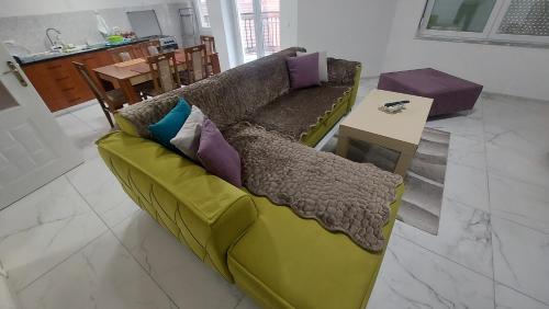 a green couch in a living room with a table at XXL APARTMENTS CiTY CENTAR in Bitola