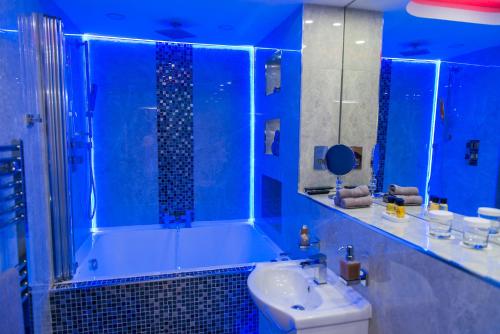 a blue bathroom with a sink and a shower at Aphrodite Suites Huddersfield in Huddersfield