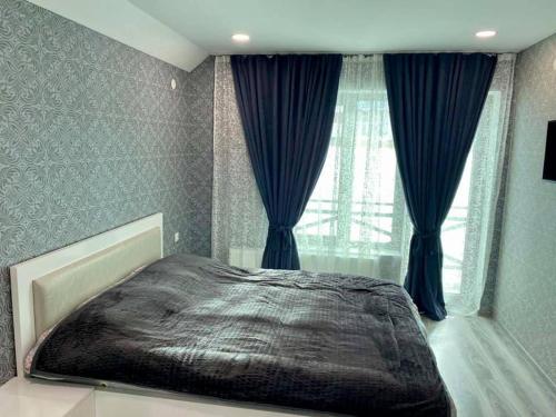 Un dormitorio con una cama grande con cortinas azules. en Villa Baghdo Bakuriani, en Bakuriani
