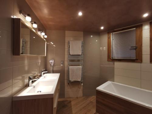 a bathroom with a sink and a bath tub at Chalet Emilie in Courchevel