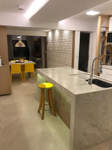 a kitchen with a sink and a yellow stool at Apartamento térreo Aquaville in Aquiraz