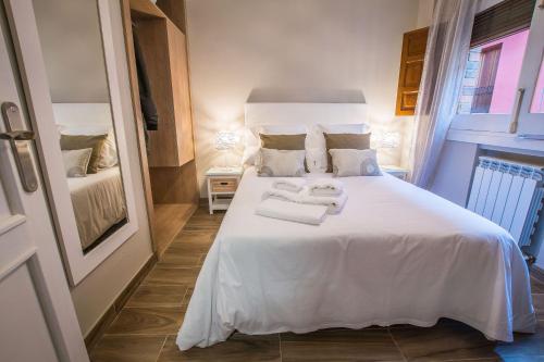 a bedroom with a white bed with towels on it at Ibericabeds Plaza Nueva Suite 21 in Granada