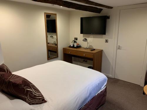 a bedroom with a bed and a desk with a television at Best Western Plus Sheffield Mosborough Hall Hotel in Sheffield