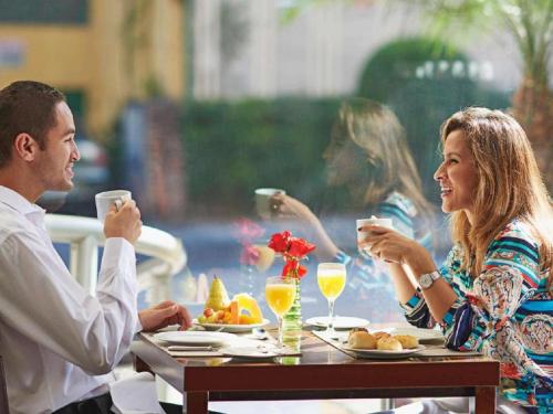 圣保罗圣保罗保利斯塔美居酒店的坐在桌子上喝饮料的男人和女人