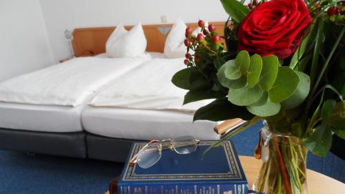 a vase of flowers on a table next to a bed at Hotel Am Weyerhof in Kerpen
