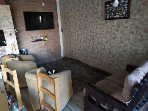 ein Wohnzimmer mit 2 Stühlen und einem TV an der Wand in der Unterkunft CASA PRAIA BEIRA MAR COM PISCINA 5 QUARTOS ACOMODA 12 pessoas in Imbé