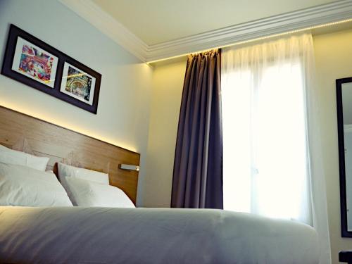 a hotel room with a bed and a window at Hôtel Eiffel XV in Paris
