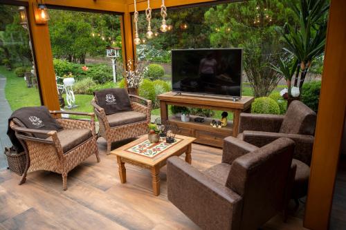 a living room with couches and a television on a patio at Hotel Pousada do Conde in Canela