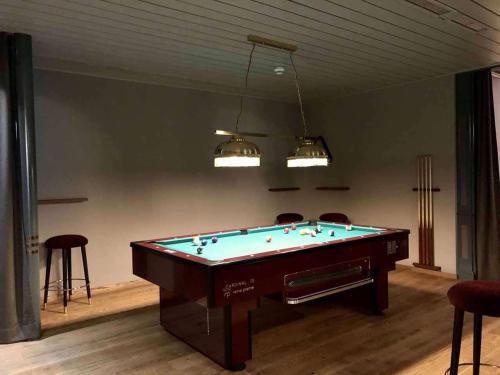 a pool table in a room with chairs and lights at Hotel Simmenhof in Lenk
