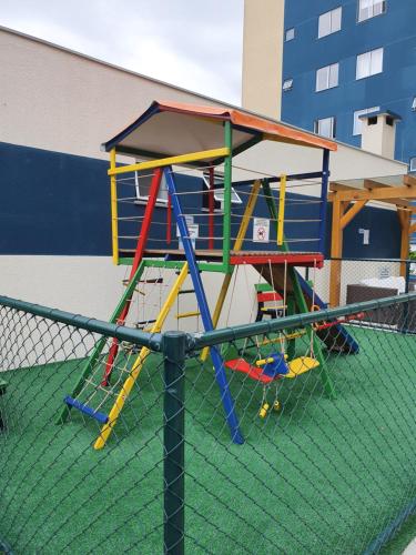 a playground with a play structure on top of a fence at Apto de Praia Fiji 1102 in Piçarras