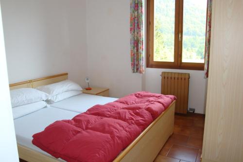 sypialnia z łóżkiem z czerwonym kocem w obiekcie Villaggio Santa Lucia w mieście Ledro