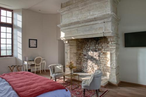 a bedroom with a fireplace with a bed and chairs at Château de Bernesq in Bernesq