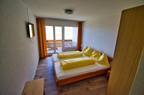 1 dormitorio con 2 camas con almohadas amarillas en Hotel Jungfrau en Fiesch
