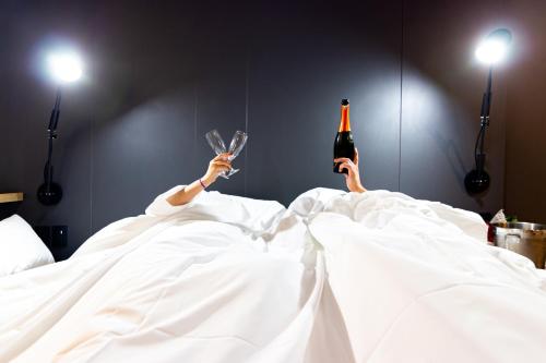 a person laying in bed with a bottle of wine at Novotel Criciuma in Criciúma