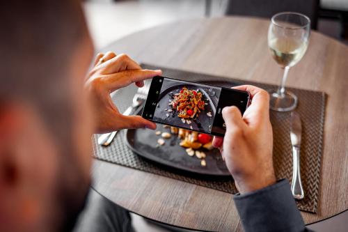 a man taking a picture of a plate of food at Novotel Criciuma in Criciúma