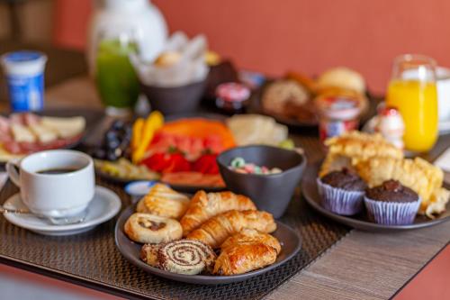 a table topped with plates of pastries and cups of coffee at Novotel Criciuma in Criciúma