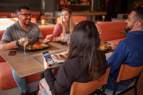 a group of people sitting around a table in a restaurant at Novotel Criciuma in Criciúma