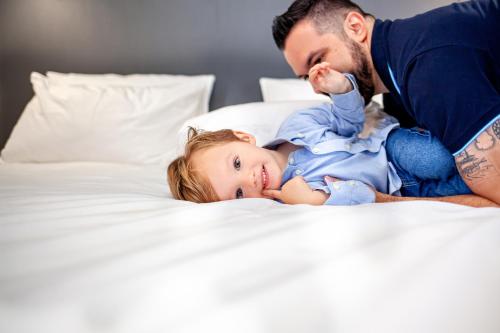 a man playing with a child on a bed at Novotel Criciuma in Criciúma
