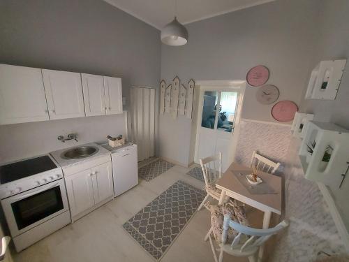 uma cozinha com armários brancos, um lavatório e uma mesa em Cozy apartment in Kikinda em Kikinda