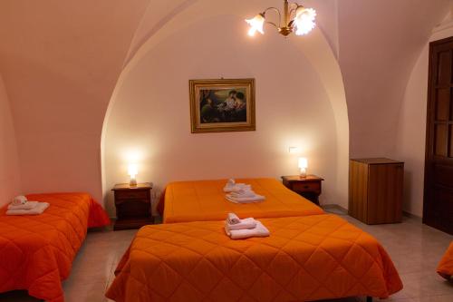 two beds in a room with orange sheets at La Masseria Hotel Ristorante Centro Benessere in Cocumola