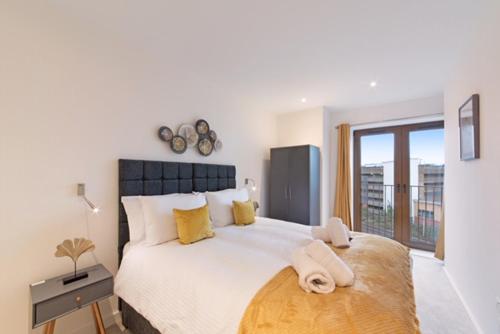 1 dormitorio blanco con 1 cama grande con almohadas amarillas en LillyRose Serviced Apartments - St Albans City Centre, Parking, en Saint Albans