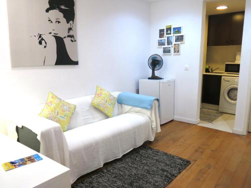 a living room with a white couch and a kitchen at Wonderful Studio in Lisbon in Lisbon