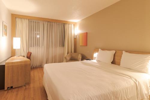 a hotel room with a large bed and a window at Novotel Porto Alegre Airport in Porto Alegre