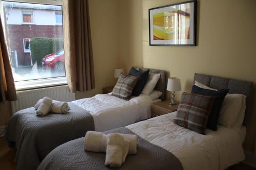 two beds in a hotel room with a window at Carvetii - Quentin House - Near Hospital, max 7 ppl in Carlisle