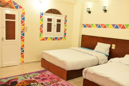 a bedroom with two beds and a window and a door at Bob Marley Guest House in Aswan
